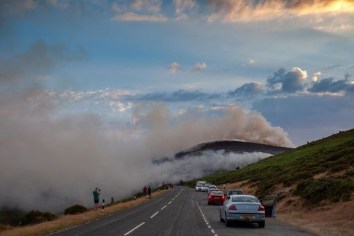 Public spectators watching the moorland fire at Llantysilio Mountain along the Horseshoe Pass, Corwen near Llangollen as the fire burns over the mountain due to heatwave temperatures in the UK