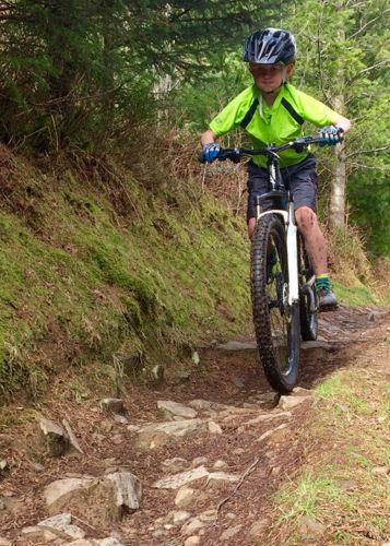 Bachgen ar gefn beic mynydd ar lwybr