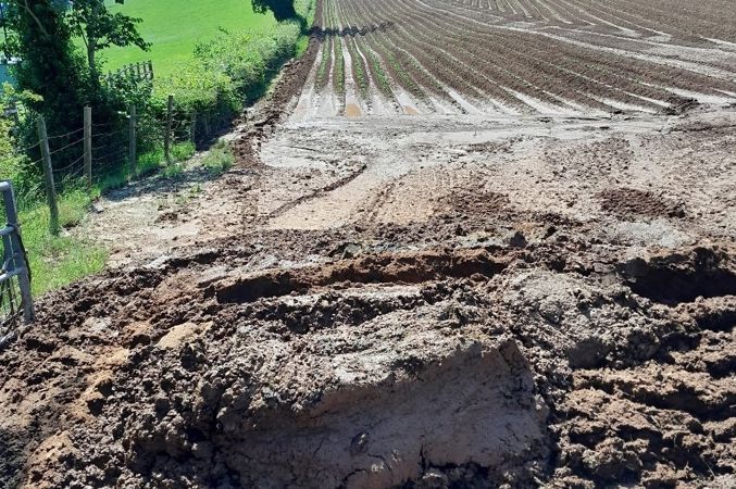 A farmer's field with soil washed down to the bottom of a slope A farmer's field with soil washed down to the bottom of a slope