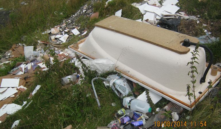Image of a fly tipping incident where materials have been dumped in a field 