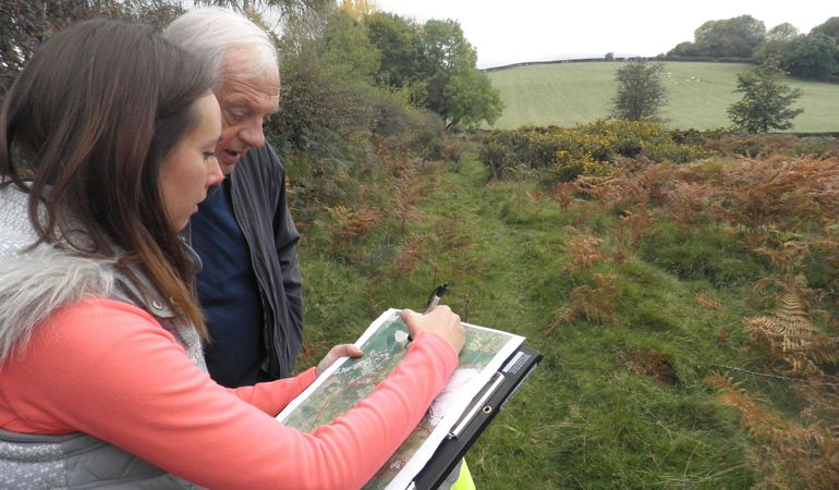 Two people marking on a map where to cut on the Halkyn Mountain Two people marking on a map where to cut on the Halkyn Mountain