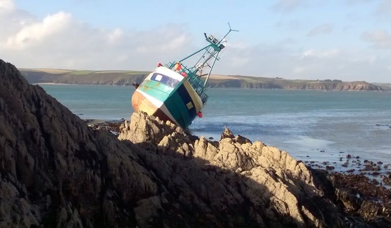 A small fishing boat stranded on some rocks A small fishing boat stranded on some rocks