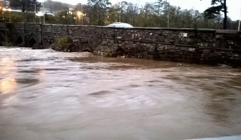 Fast flowing high river against an old brick bridge Fast flowing high river against an old brick bridge