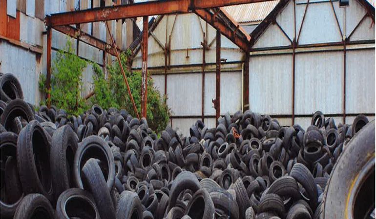 Lots of car tyres piled up outside a warehouse Lots of car tyres piled up outside a warehouse