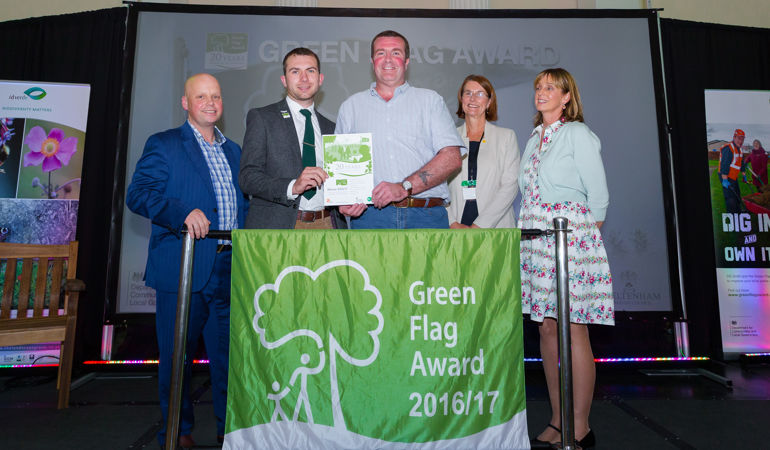 a group of 5 people standing behind a green flag awards 2016-17 banner a group of 5 people standing behind a green flag awards 2016-17 banner