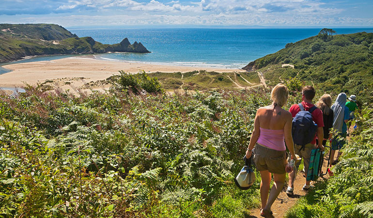 Group of people walking towards the beach at 3 Cliffs Bay Gower Group of people walking towards the beach at 3 Cliffs Bay Gower