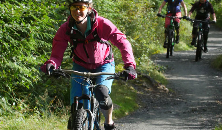 Image of a woman mountain biking with two cyclists in the background Image of a woman mountain biking with two cyclists in the background