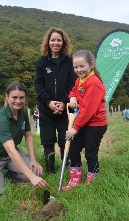 Rebecca Good (Woodland Trust), Kate Thomson (NRW) and a school girl planting a tree Rebecca Good (Woodland Trust), Kate Thomson (NRW) and a school girl planting a tree