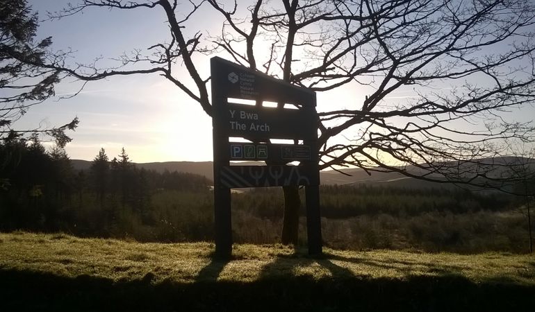 Y Bwa vistor centre sign with the sun setting in the background behind a silhouette of a tree Y Bwa vistor centre sign with the sun setting in the background behind a silhouette of a tree