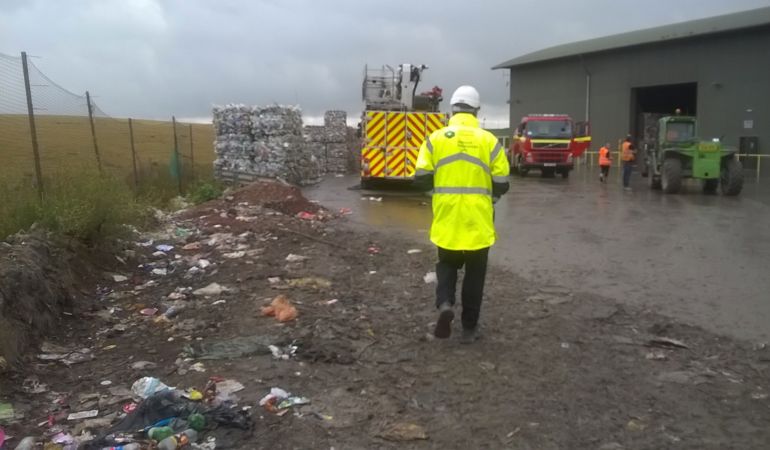 NRW officer at the landfill site with fire engine and waste in the background NRW officer at the landfill site with fire engine and waste in the background