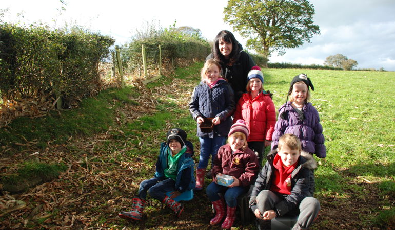 A woman and a group of children collecting acorns A woman and a group of children collecting acorns
