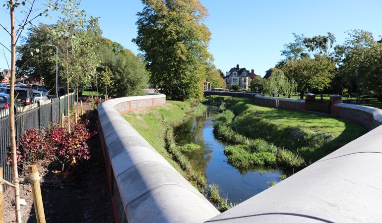 Photo of the green banks of the Roath Brook with new flood walls with grey coping stones running alongside the banks Photo of the green banks of the Roath Brook with new flood walls with grey coping stones running alongside the banks