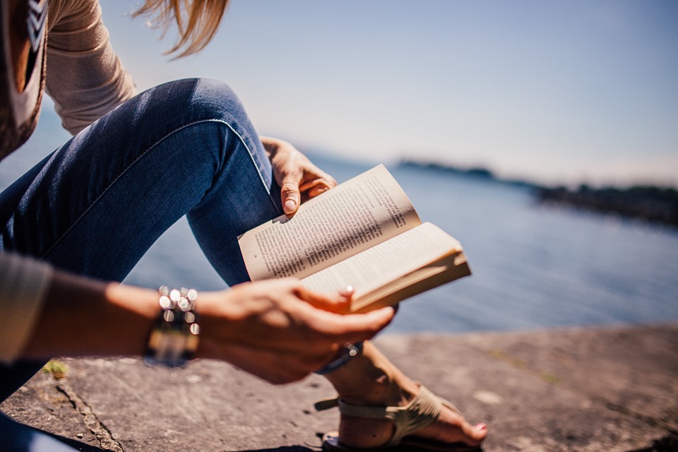 Woman reading a book next to water