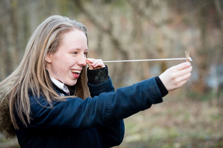 Girl using string and peg to measure tree height