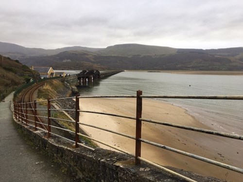 An image of the Mawddach estuary with the railway bridge across from Barmouth to Fairbourne. The image shows how closely the train tracks are to the edge of the coastline in this area