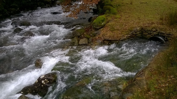 Photograph showing a partially submerged outfall channel aligned at 450 to the direction of main river flow