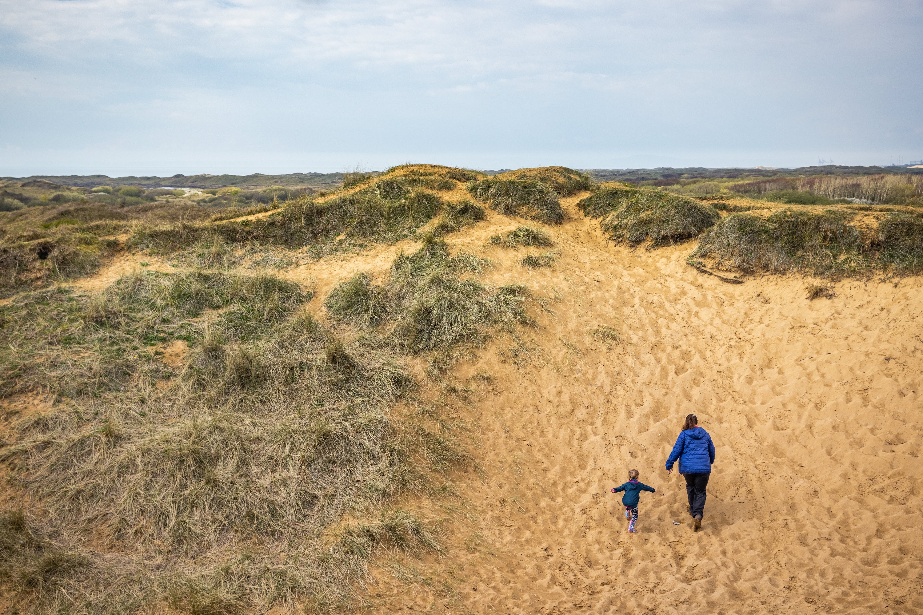 Menywod a phlentyn yn cerdded i fyny sandune 