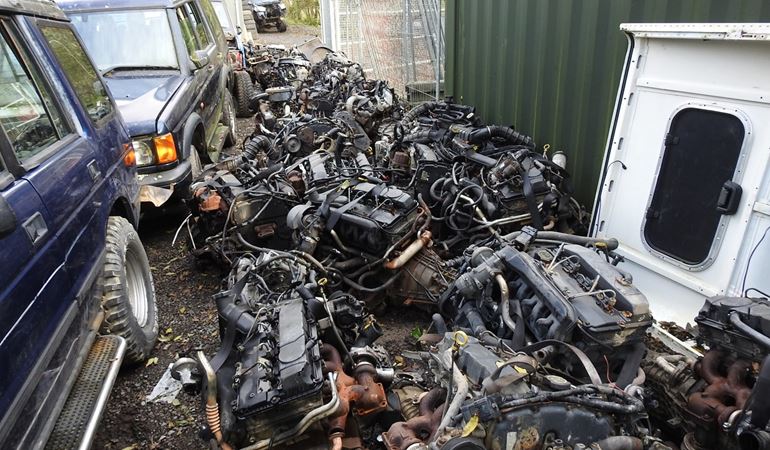 Two 4x4s and many engines on the floor in a yard