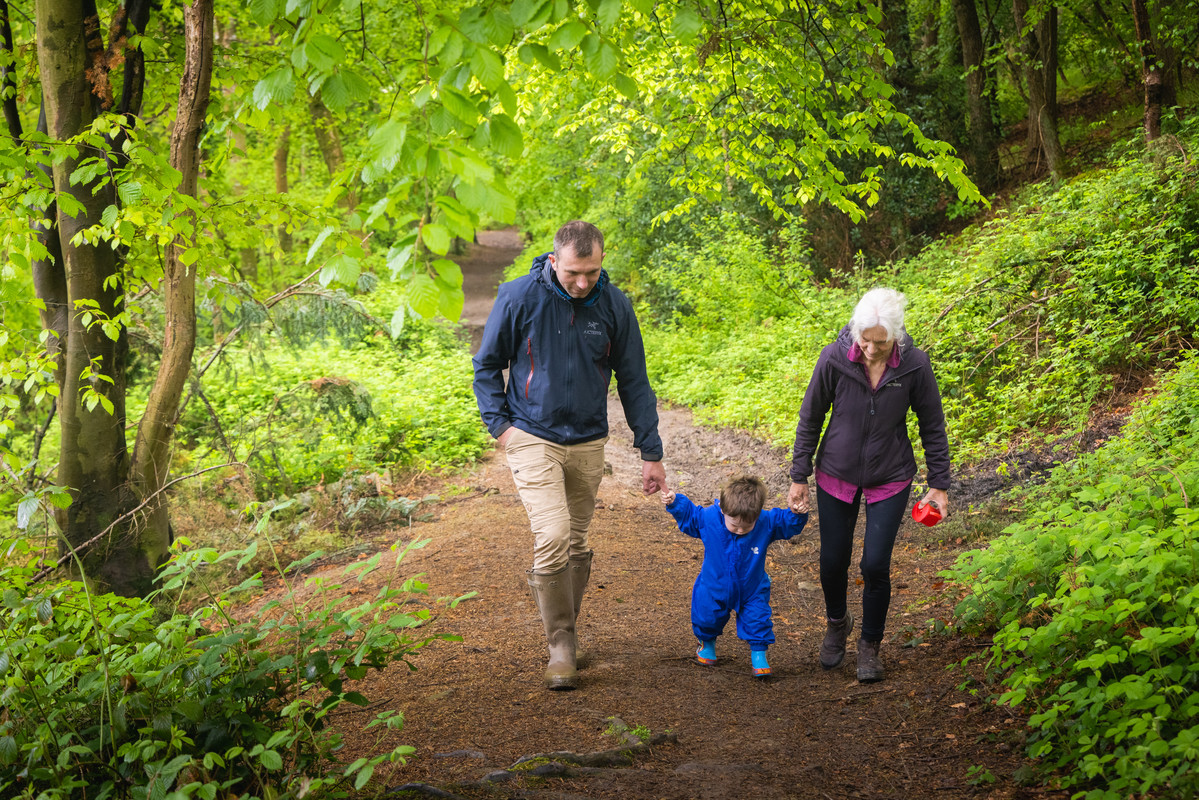 Two adults and a child walking through a woodland