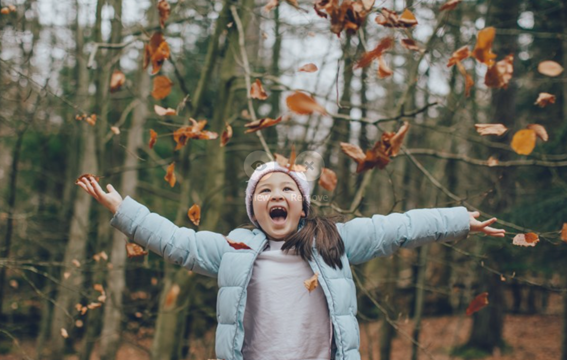 A girl throwing leaves in a forest