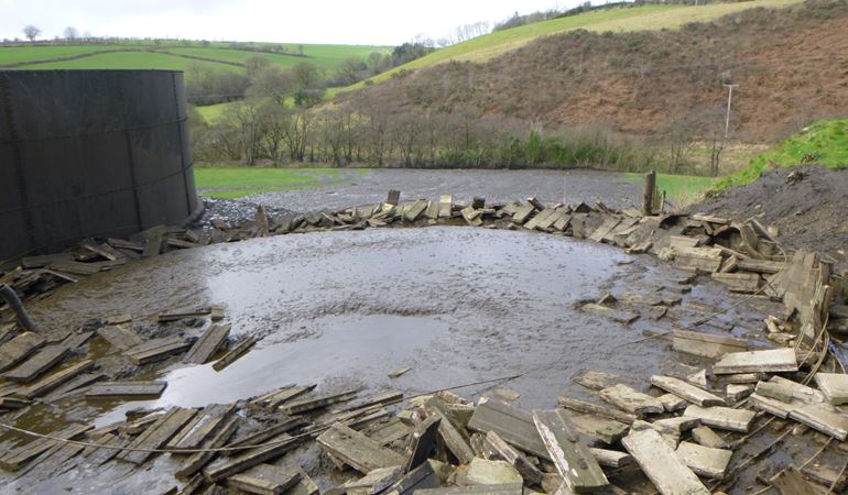 Collapsed slurry store with slurry running into the stream