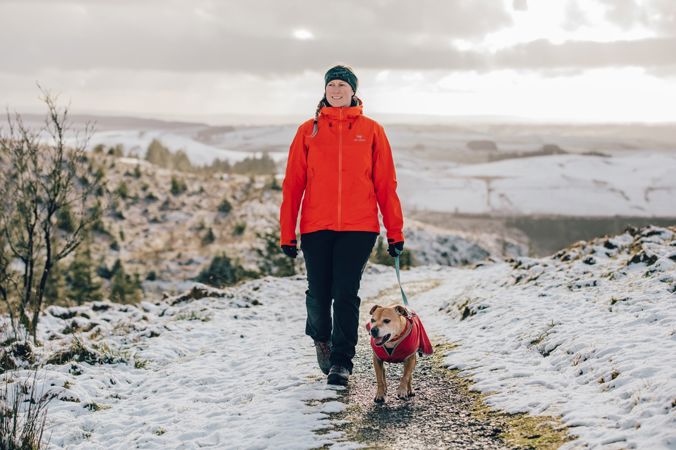 A woman and dog walking on a snowy hill A woman and dog walking on a snowy hill