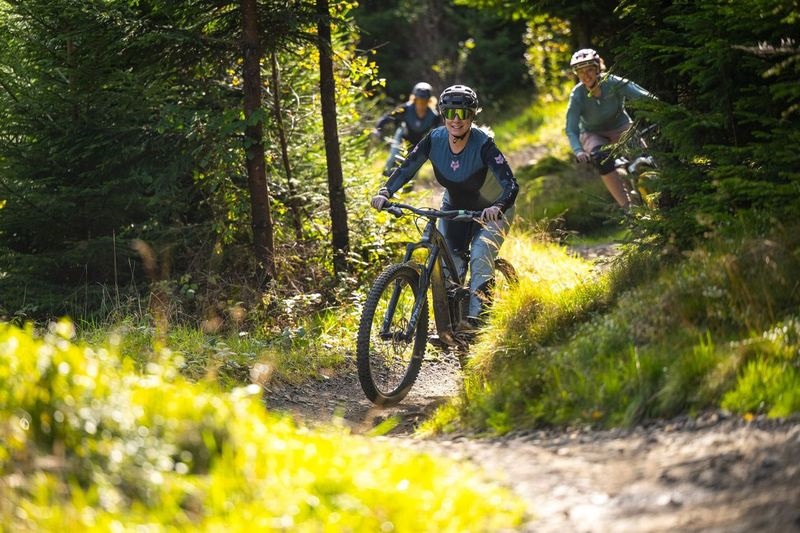 Three women riding along a trail in BikePark Wales